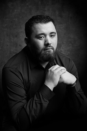 A young man poses seriously in a studio session for his headshot.