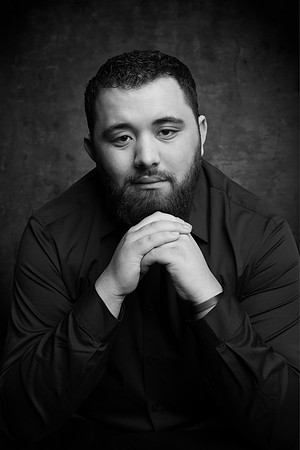 A serious portrait of a young man inside of the studio.