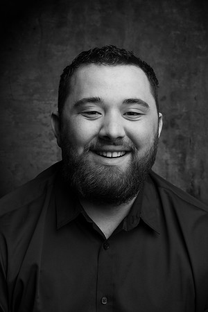 A black and white portrait of a young man inside of the studio.
